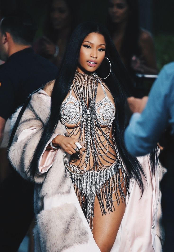 Nicki Minaj dressed in a two-piece bejeweled outfit and fur coat
